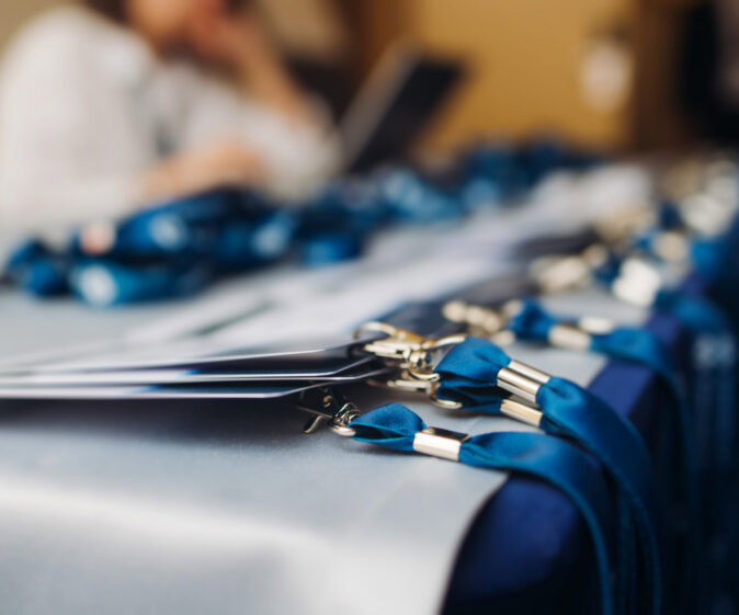 Process Of Checking In On Conference Congress Forum Event, Registration Desk Table, Visitors And Attendees Receiving Lanyard With Name Badge And Entry Wristband Bracelet And Register Electronic Ticket